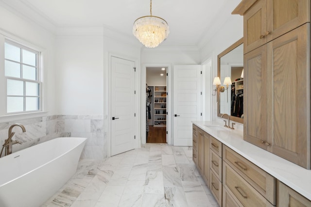 full bath with marble finish floor, a freestanding tub, vanity, and crown molding