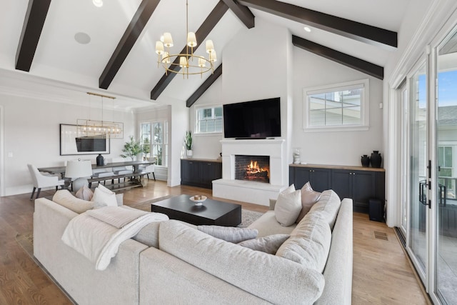 living room with a chandelier, a wealth of natural light, and light wood-style flooring