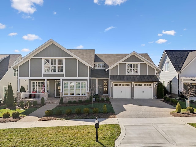 view of front facade featuring a garage, concrete driveway, covered porch, a standing seam roof, and a front lawn