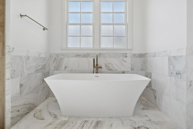 full bathroom with a freestanding tub, a wainscoted wall, and marble finish floor