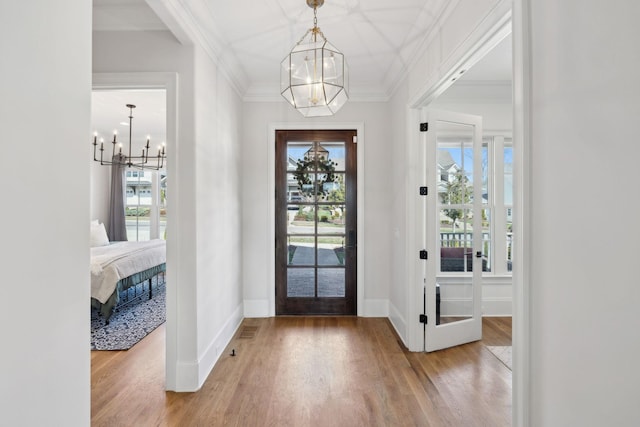 foyer featuring a chandelier, ornamental molding, and wood finished floors