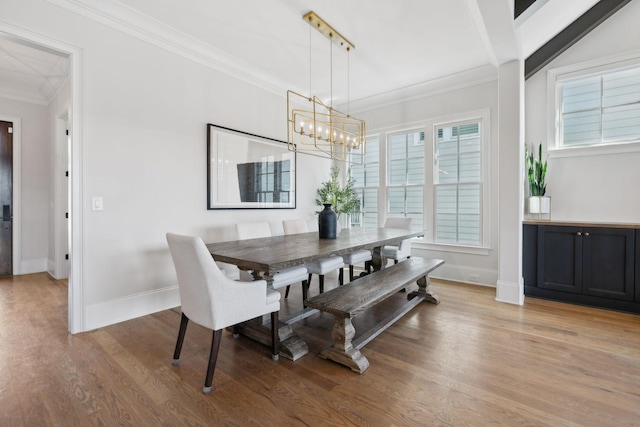 dining area with light wood-type flooring, baseboards, ornamental molding, and a notable chandelier