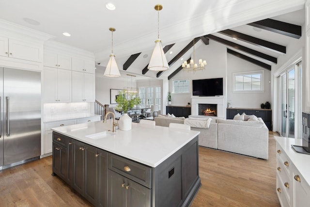 kitchen featuring a chandelier, lofted ceiling with beams, a sink, white cabinetry, and stainless steel built in fridge