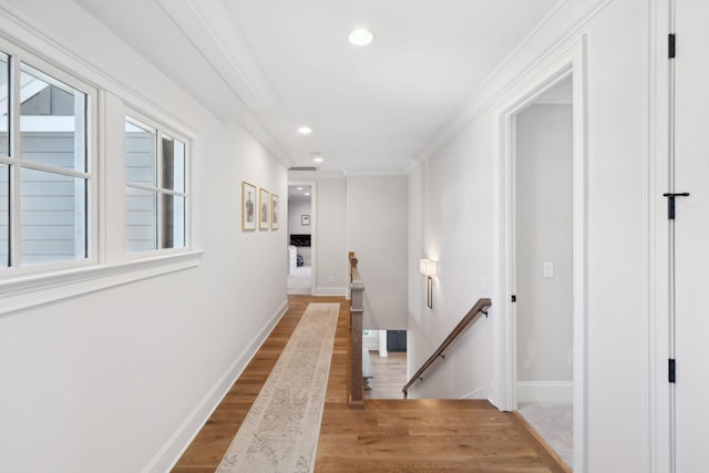 hall featuring baseboards, wood finished floors, crown molding, an upstairs landing, and recessed lighting