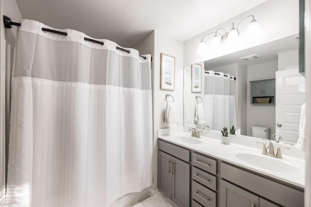 full bathroom featuring visible vents, a sink, toilet, and double vanity