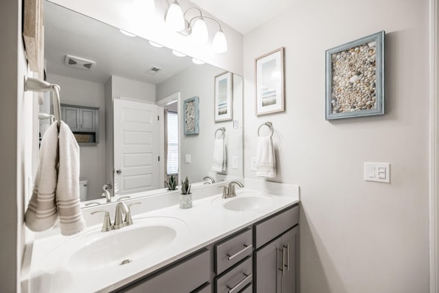 full bath with visible vents, a sink, toilet, and double vanity