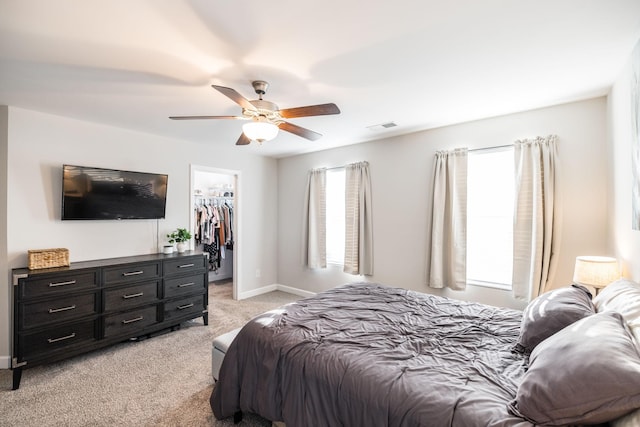 bedroom featuring light carpet, visible vents, baseboards, a closet, and a walk in closet