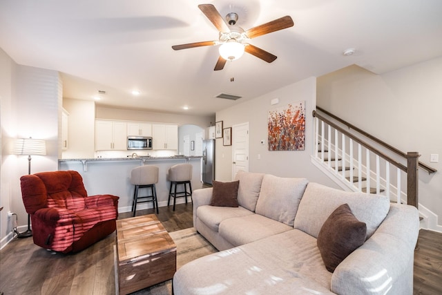 living area featuring dark wood-style flooring, visible vents, baseboards, and stairs