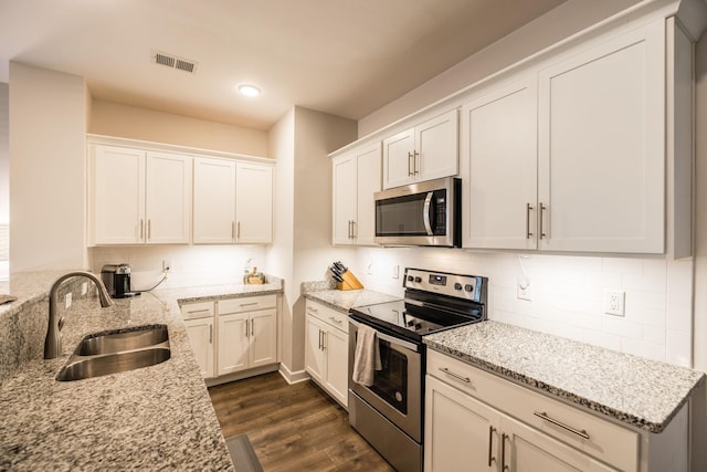 kitchen featuring appliances with stainless steel finishes, dark wood finished floors, a sink, and tasteful backsplash