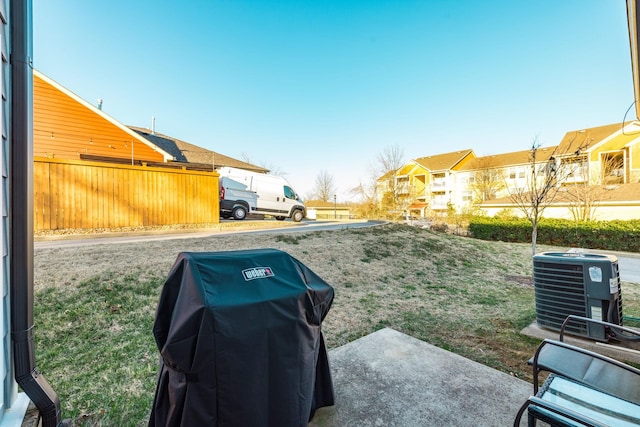 view of yard featuring central AC unit, fence, and a residential view