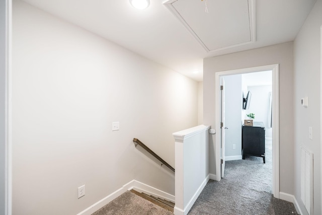 corridor featuring attic access, carpet, baseboards, and an upstairs landing