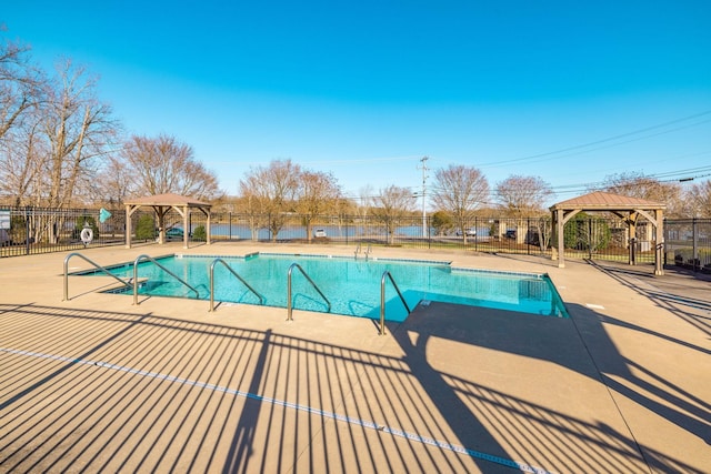 community pool with a patio area, fence, and a gazebo