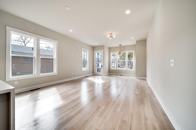 empty room with light wood-style floors, visible vents, baseboards, and recessed lighting