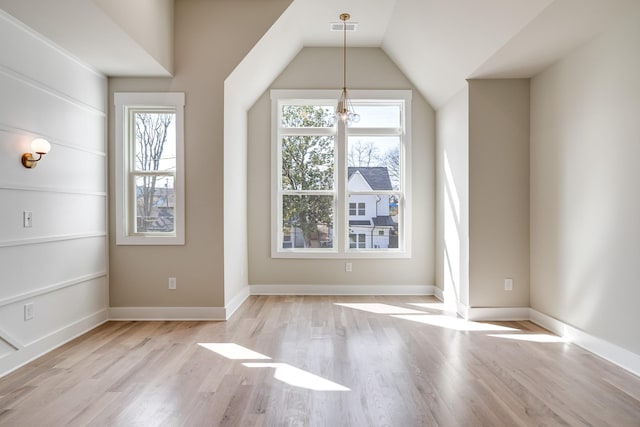 unfurnished dining area featuring lofted ceiling, visible vents, baseboards, and wood finished floors