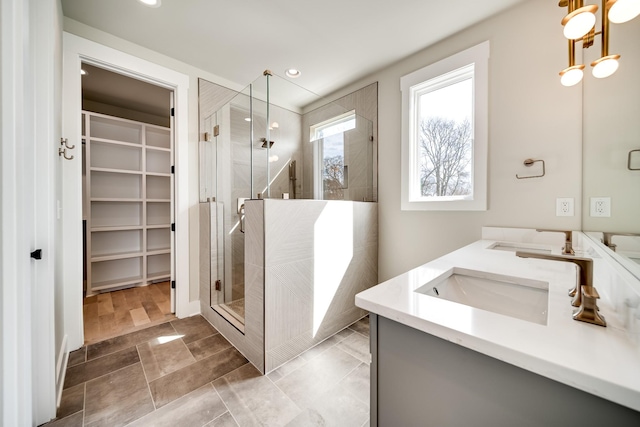 bathroom featuring a stall shower, a sink, a spacious closet, and double vanity