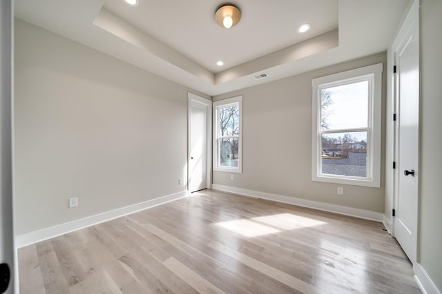 empty room featuring baseboards, visible vents, a raised ceiling, and a wealth of natural light