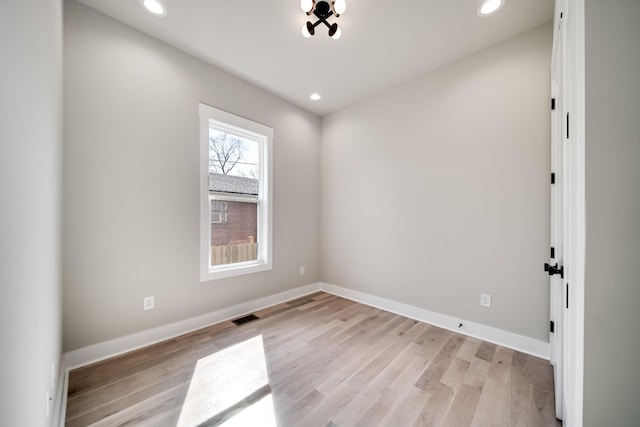 spare room featuring light wood-style floors, baseboards, and visible vents