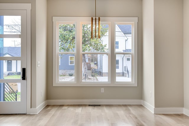 unfurnished dining area featuring light wood finished floors and baseboards