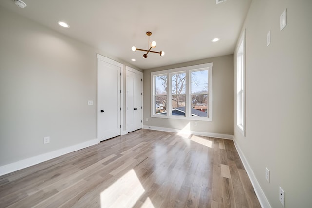 empty room featuring light wood-style floors, baseboards, a chandelier, and recessed lighting