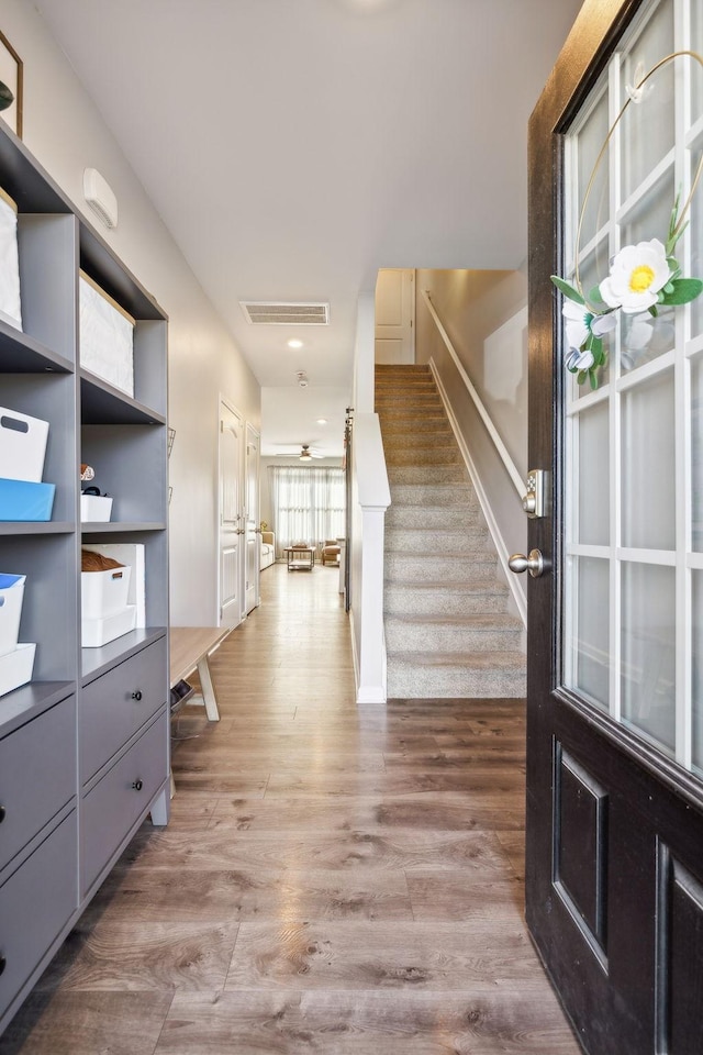 foyer entrance featuring stairway, wood finished floors, and visible vents