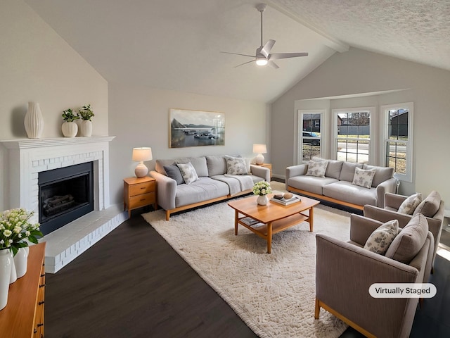 living room with a ceiling fan, lofted ceiling with beams, dark wood-style floors, a textured ceiling, and a fireplace