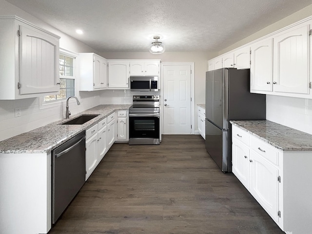 kitchen with appliances with stainless steel finishes, white cabinetry, and a sink