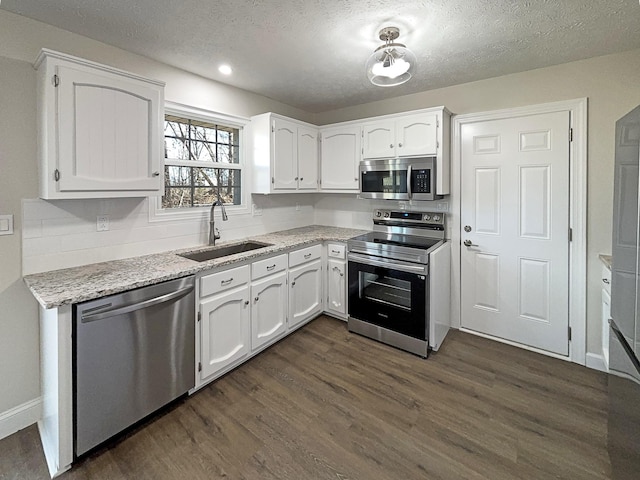 kitchen with white cabinets, dark wood finished floors, stainless steel appliances, a textured ceiling, and a sink