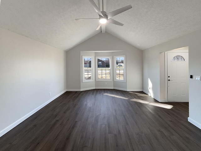 interior space featuring dark wood-type flooring, lofted ceiling, a textured ceiling, and baseboards