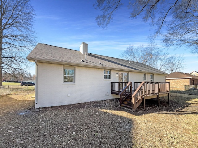 back of house with a deck, brick siding, fence, roof with shingles, and a chimney