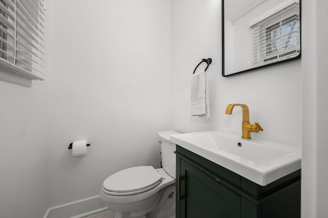 half bathroom featuring vanity, toilet, and baseboards