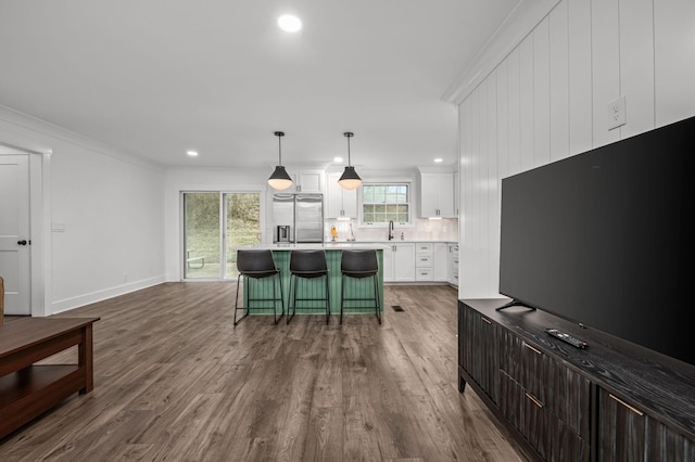 kitchen featuring a sink, white cabinetry, stainless steel fridge with ice dispenser, decorative backsplash, and a kitchen bar