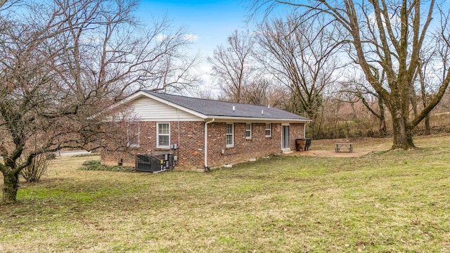 view of side of property with brick siding, a lawn, and central air condition unit