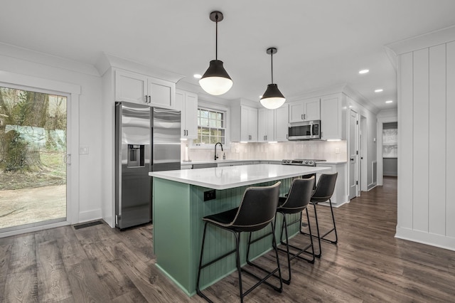 kitchen featuring stainless steel appliances, light countertops, backsplash, dark wood-type flooring, and white cabinets