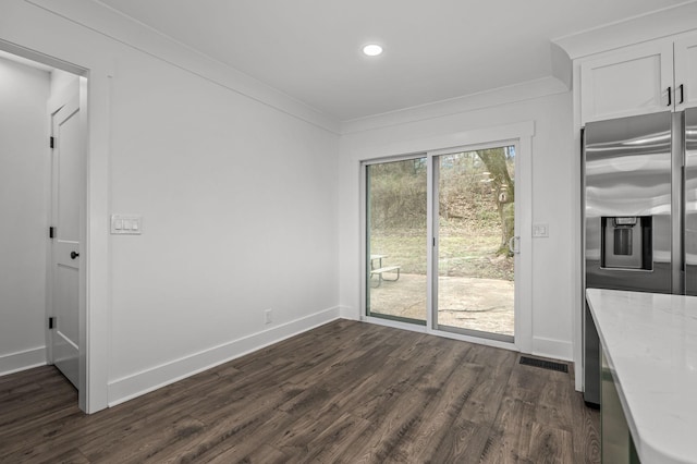 unfurnished dining area with dark wood-style floors, visible vents, crown molding, and baseboards