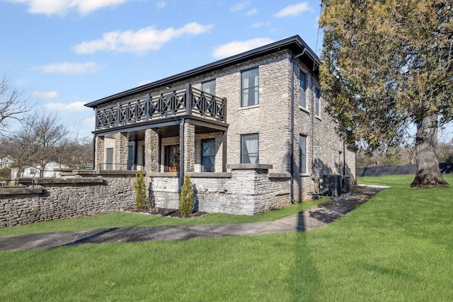 view of front of property with a front yard, stone siding, and a balcony