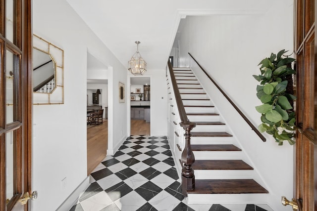 foyer entrance with stairs, a chandelier, and baseboards