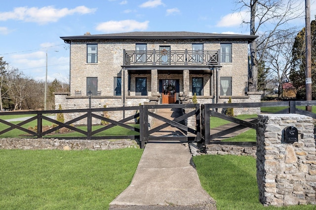 view of front of property with a balcony, a fenced front yard, and a gate