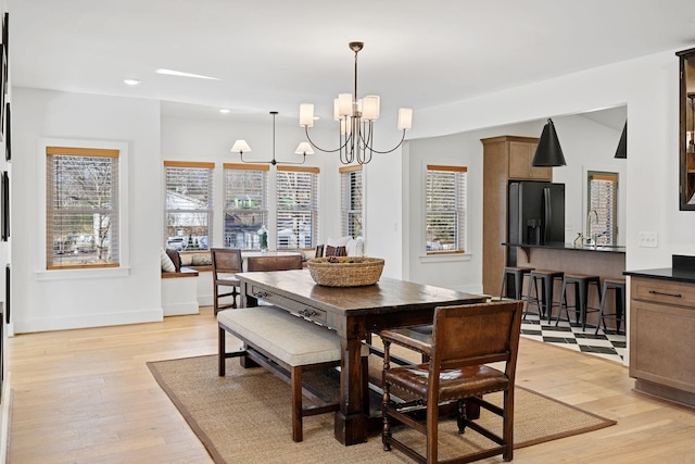 dining space with light wood-type flooring, baseboards, a notable chandelier, and recessed lighting