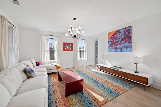 living room featuring baseboards, visible vents, a chandelier, and wood finished floors