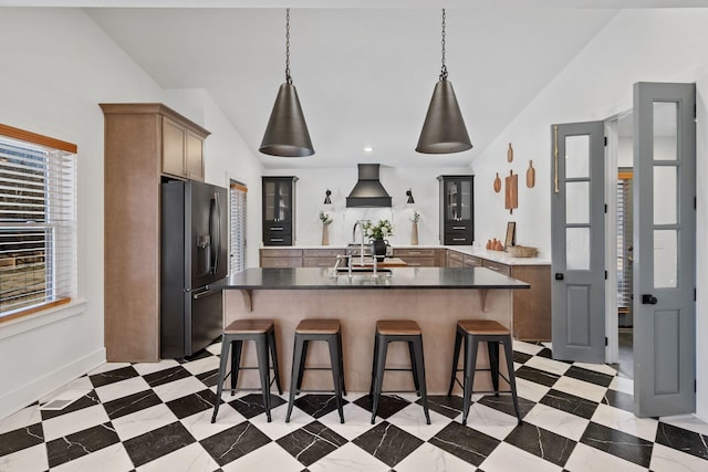 kitchen featuring stainless steel refrigerator with ice dispenser, light floors, vaulted ceiling, a sink, and a kitchen breakfast bar