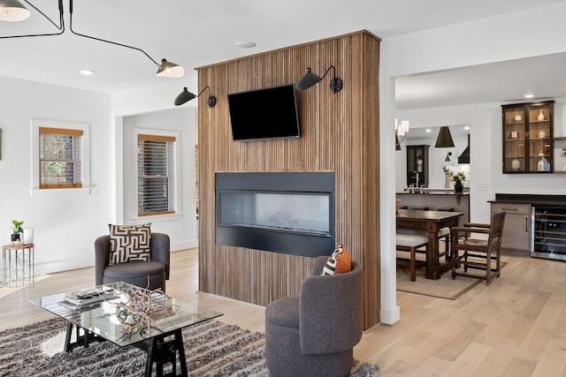 living area with light wood-type flooring, beverage cooler, a large fireplace, and recessed lighting