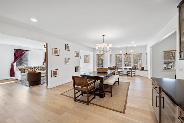 dining area with beverage cooler, light wood-style floors, plenty of natural light, and a notable chandelier