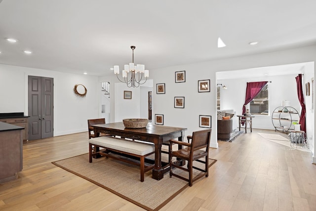 dining room with light wood-type flooring, an inviting chandelier, baseboards, and recessed lighting