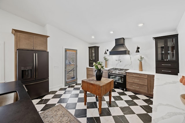 kitchen featuring stainless steel stove, refrigerator with ice dispenser, vaulted ceiling, glass insert cabinets, and custom range hood