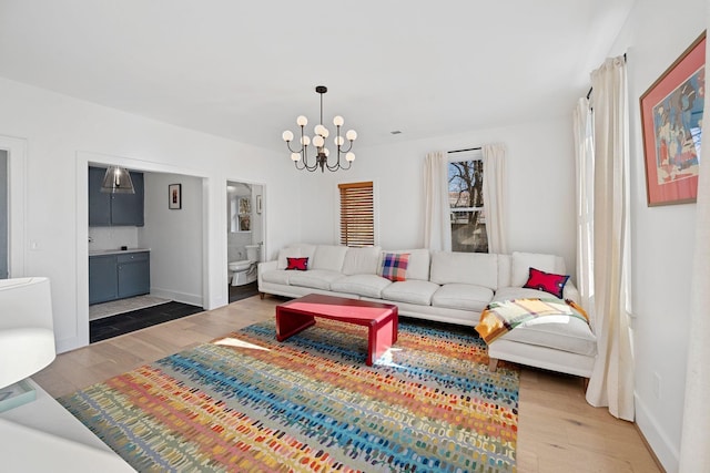 living area with an inviting chandelier, baseboards, and wood finished floors