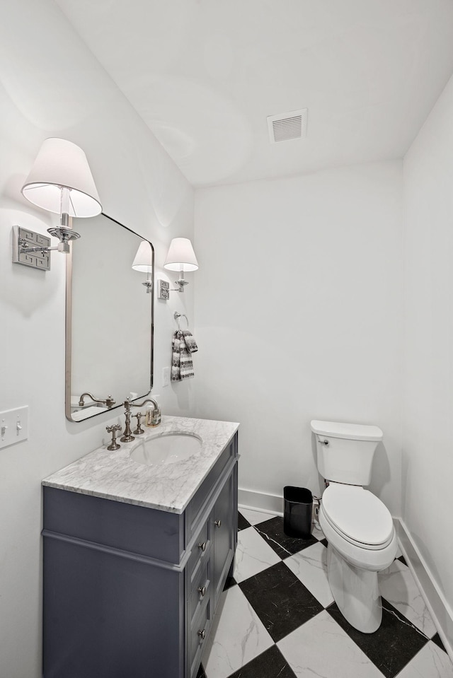 bathroom featuring visible vents, baseboards, toilet, marble finish floor, and vanity