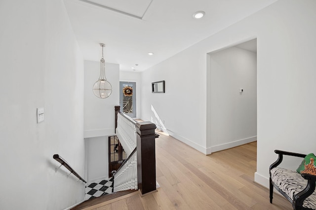 hall with recessed lighting, light wood-type flooring, an upstairs landing, and baseboards