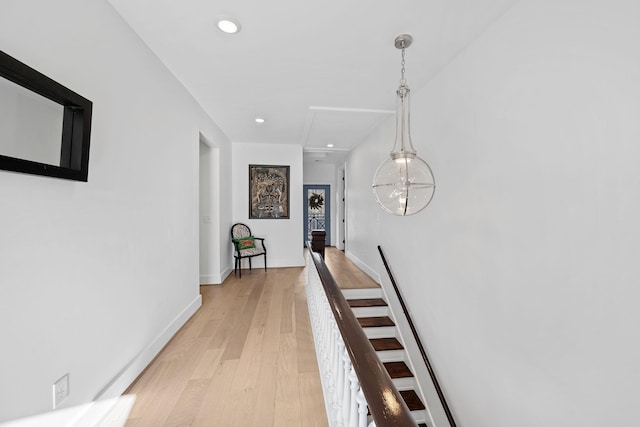 hall with an upstairs landing, recessed lighting, baseboards, and light wood finished floors