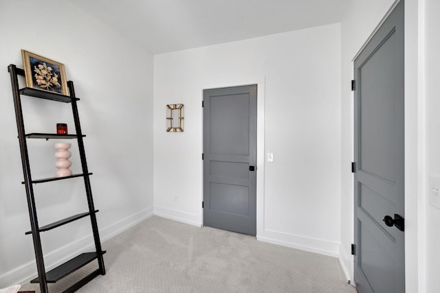 interior space featuring baseboards and light colored carpet