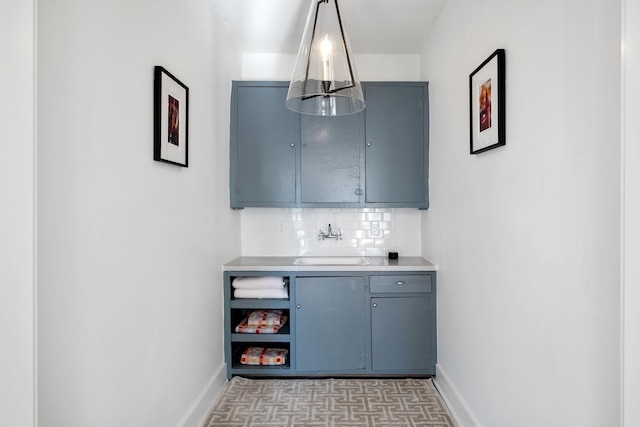 bar with backsplash, a sink, and baseboards